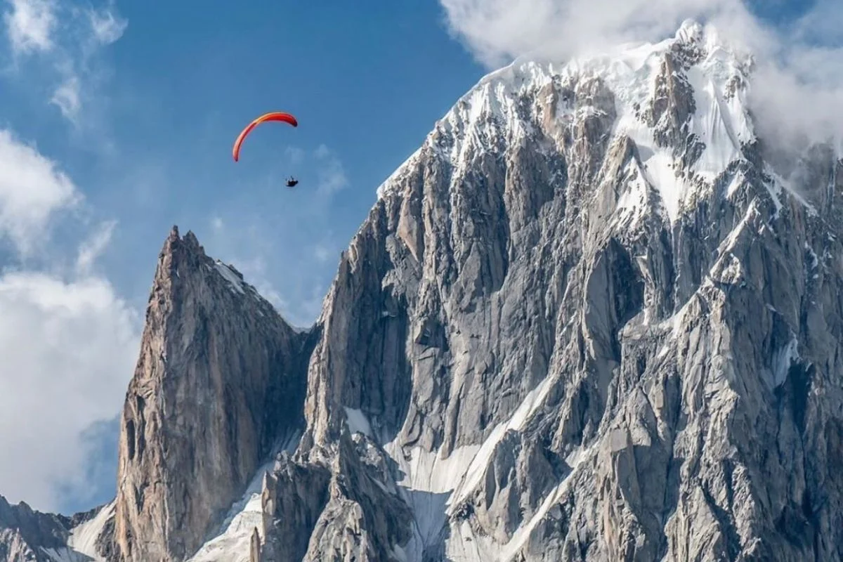 Paragliding in Pakistan over the Karakoram mountain range with snow-covered peaks and deep valleys